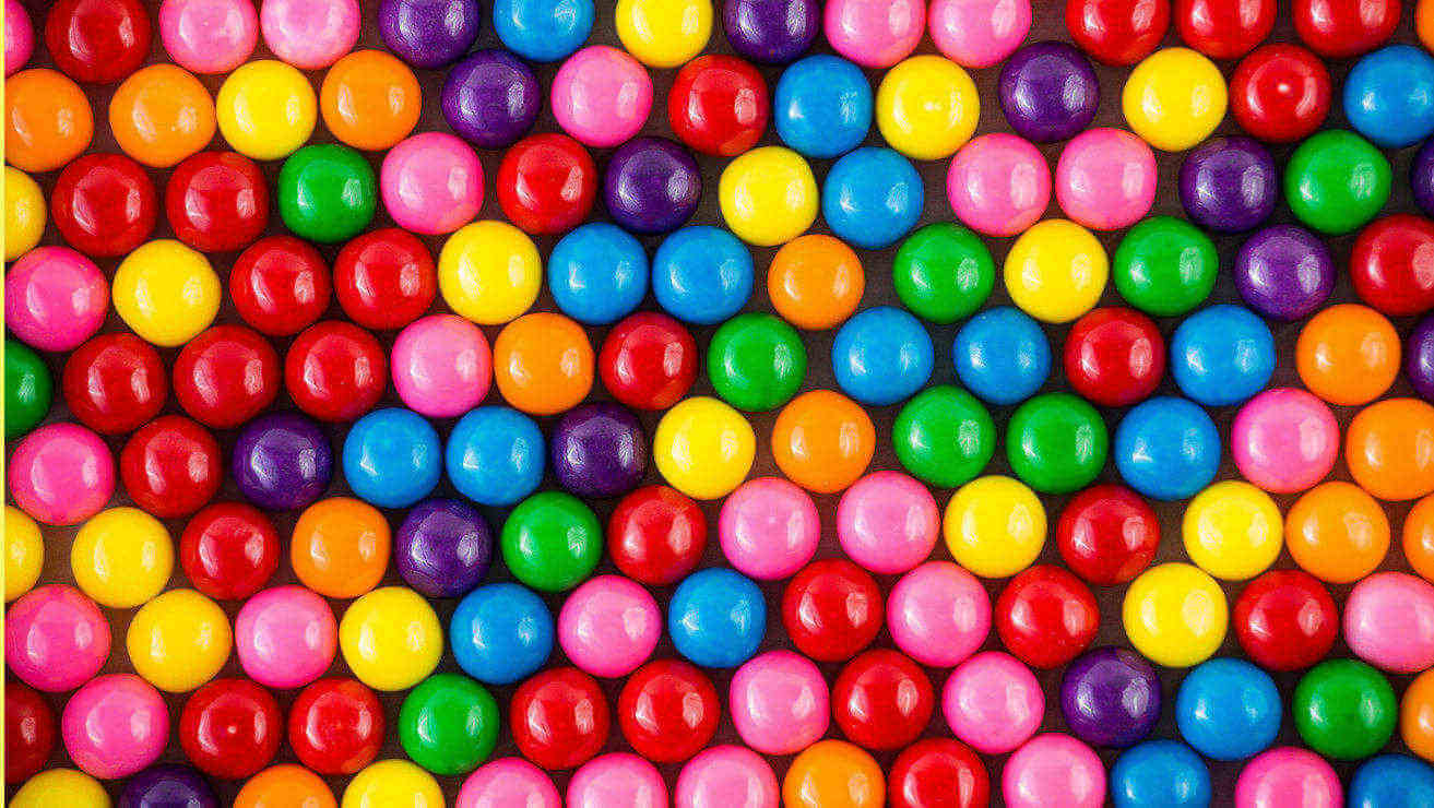 Színes (piros, rózsaszín, narancssárga, sárga, lila, zöld, kék) golyó rágógumik kiterítve egy vízszintes felületét